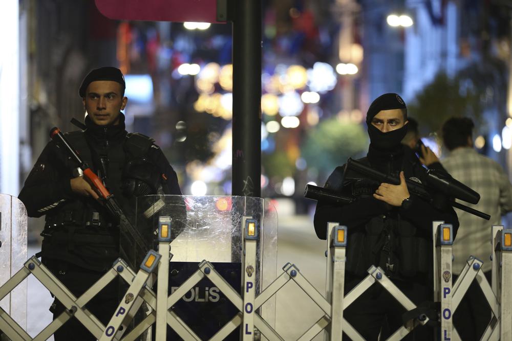 Police officers stand at the entrance the street after an explosion on Istanbul's popular pedestrian Istiklal Avenue, late Sunday, Nov. 13, 2022. A bomb rocked on a major pedestrian avenue in the heart of Istanbul on Sunday, killing six people, wounding dozens and sending people fleeing the fiery explosion. Emergency vehicles rushed to the scene on Istiklal Avenue, a popular thoroughfare lined with shops and restaurants that leads to the iconic Taksim Square.(AP Photo/Emrah Gurel)