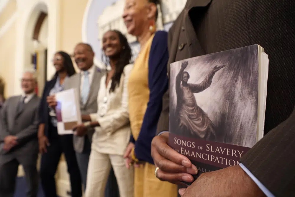 Dr. Amos C. Brown, Jr., vice chair for the California Reparations Task Force, right, holds a copy of the book Songs of Slavery and Emancipation