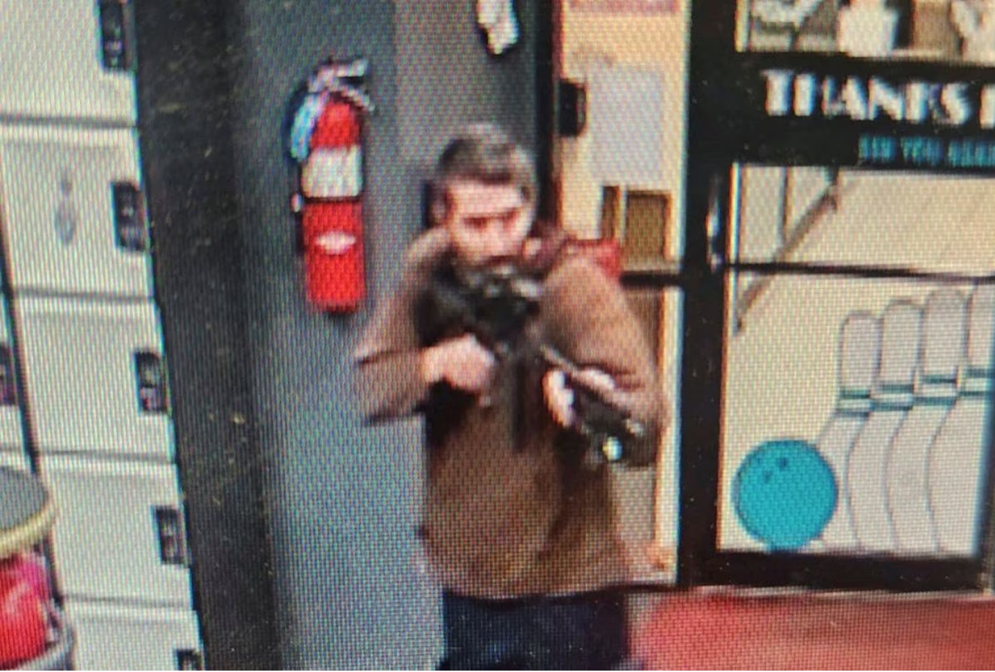 A man identified as a suspect by police points what appears to be a semiautomatic rifle, in Lewiston, Maine, U.S.