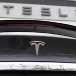 The Tesla company logo shines off the rear deck of an unsold 2020 Model X at a Tesla dealership, April 26, 2020, in Littleton, Colo.