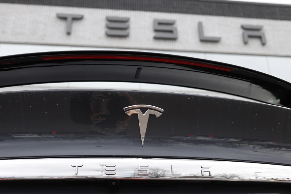 The Tesla company logo shines off the rear deck of an unsold 2020 Model X at a Tesla dealership, April 26, 2020, in Littleton, Colo.