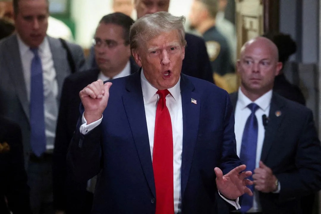 Former U.S. President Donald Trump gestures while leaving the courtroom during a break