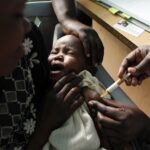 A mother holds her baby receiving a new malaria vaccine as part of a trial at the Walter Reed Project Research Center in Kombewa in Western Kenya on Oct. 30, 2009.