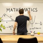 Teacher writing maths formulae on whiteboard