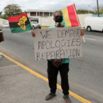A protester holds a sign during a rally to demand that the United Kingdom make reparations for slavery