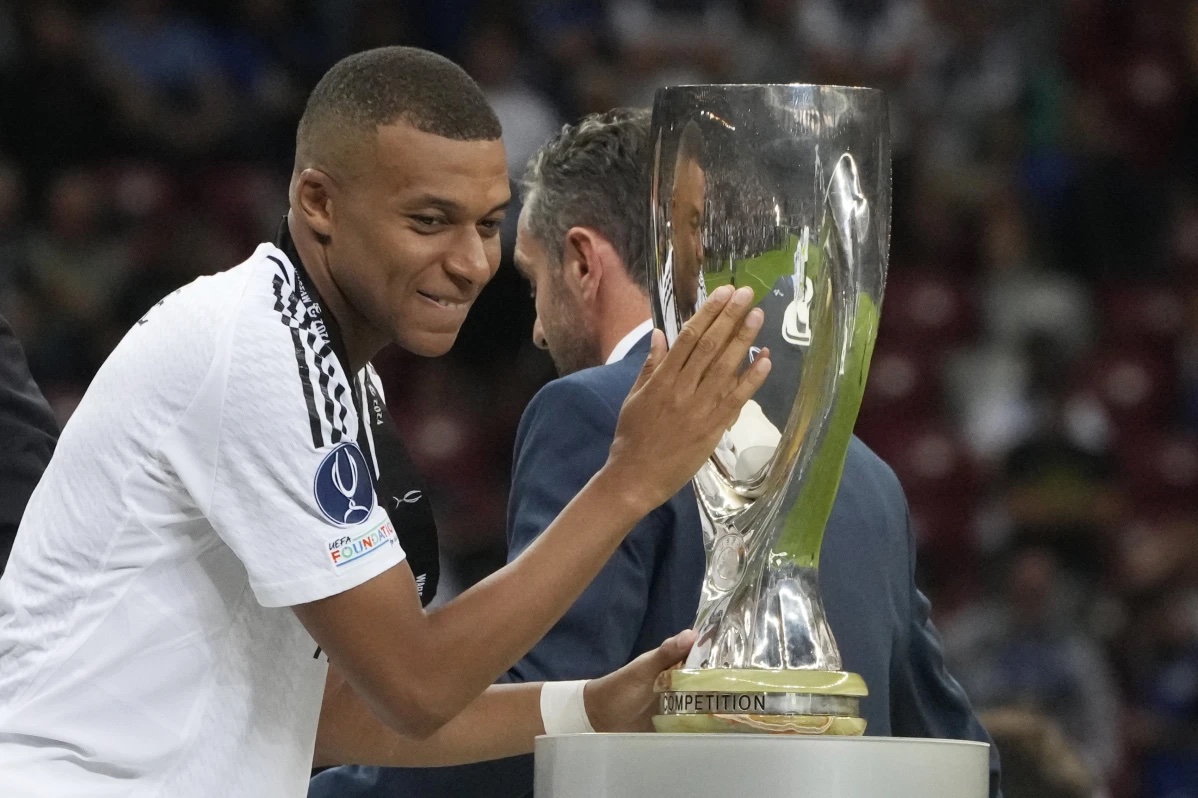Real Madrid’s Kylian Mbappe touches the trophy during the medal ceremony for the UEFA Super Cup Final soccer match between Real Madrid and Atalanta at the Narodowy stadium in Warsaw, Poland, Wednesday, Aug. 14, 2024.