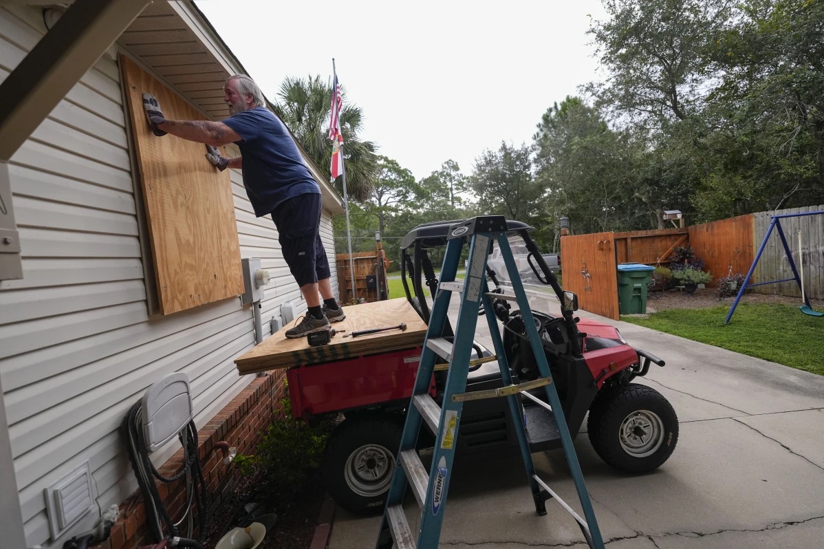 Dave McCurley boards up the windows to his home in advance of Tropical Storm Helene, expected to make landfall as a hurricane, in Ochlockonee Bay, Fla., Wednesday, Sept. 25, 2024.