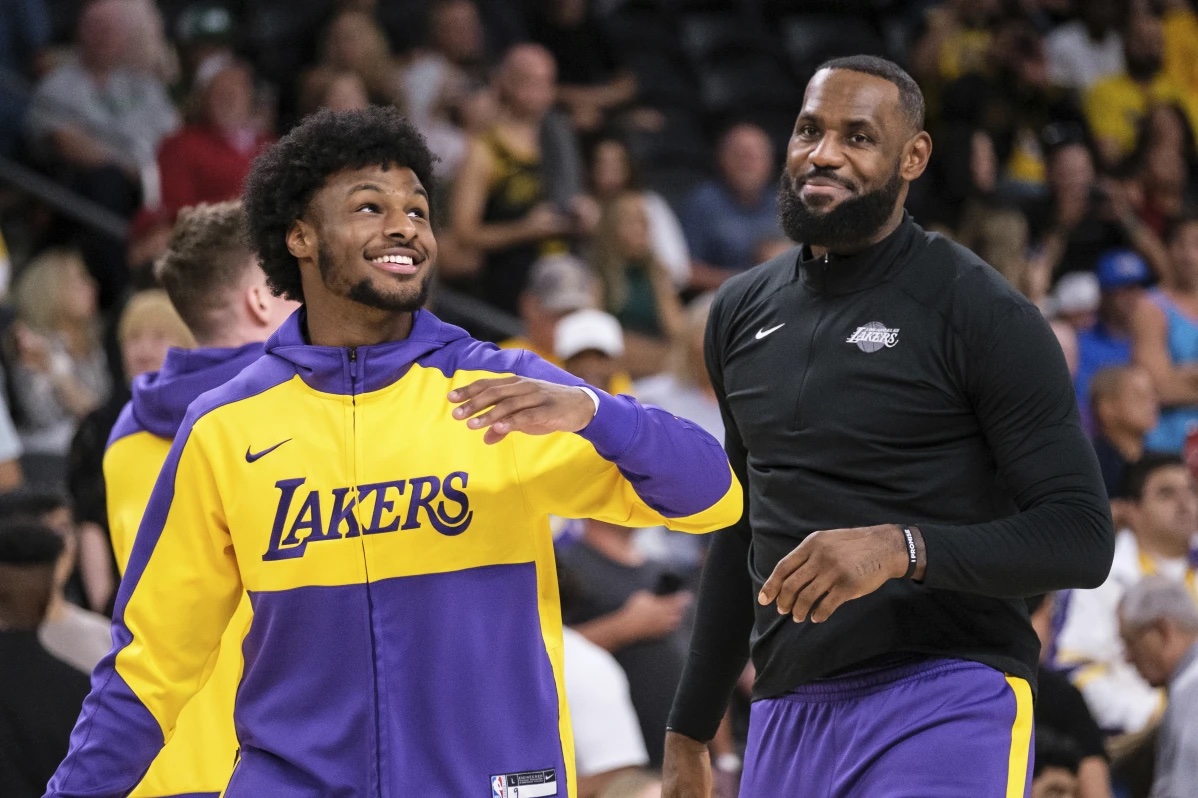 Los Angeles Lakers guard Bronny James, left, and forward LeBron James warm up before a preseason NBA basketball game against the Phoenix Suns, Sunday, Oct. 6, 2024, in Palm Desert, Calif.