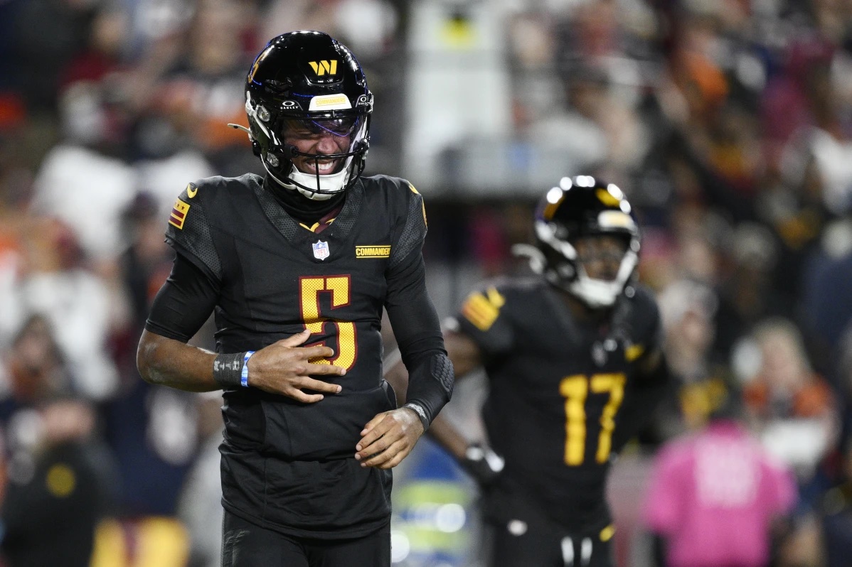 Washington Commanders quarterback Jayden Daniels (5) winces in pain after a play in the second half of an NFL football game against the Chicago Bears Sunday, Oct. 27, 2024, in Landover, Md.