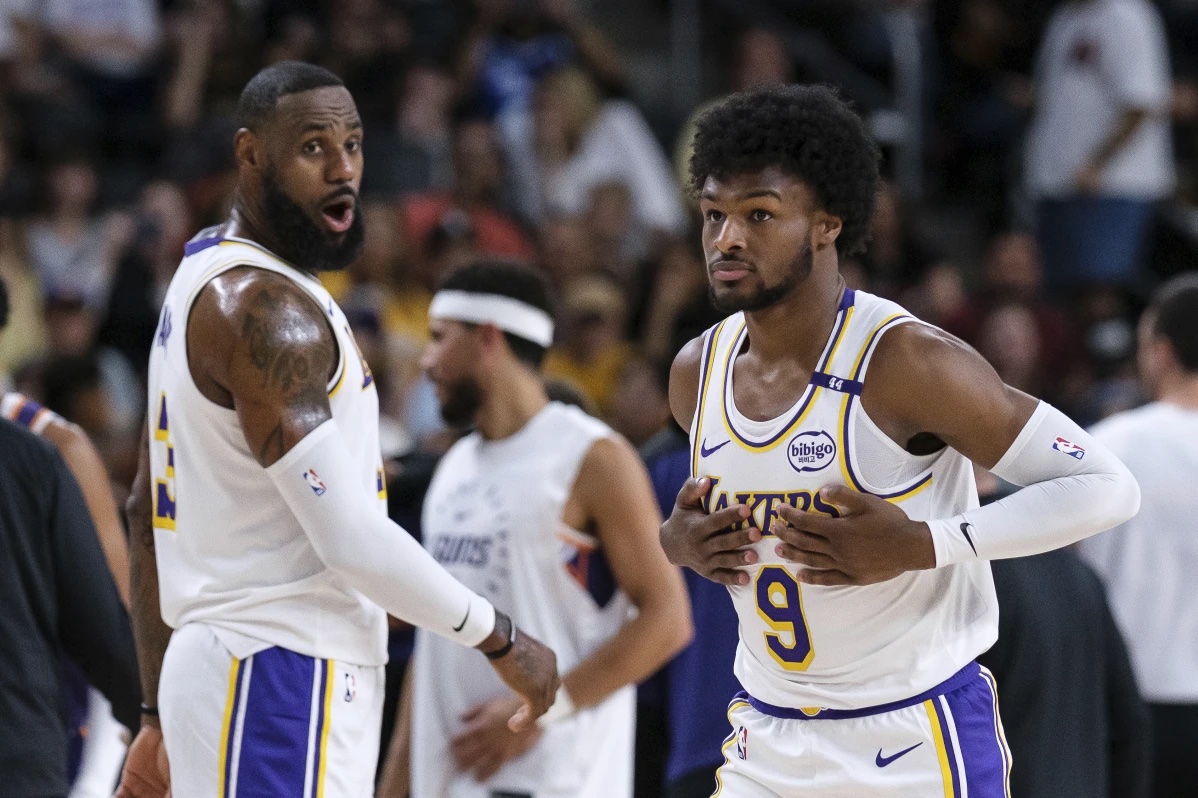 Los Angeles Lakers guard Bronny James (9), right, steps onto the court with Los Angeles Lakers forward LeBron James (23) during the first half of a preseason NBA basketball game Sunday, Oct. 6, 2024, in Palm Desert, Calif.
