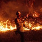 A firefighter prepares to douse flames while battling the Mountain Fire on Wednesday, Nov. 6, 2024, in Santa Paula, Calif.