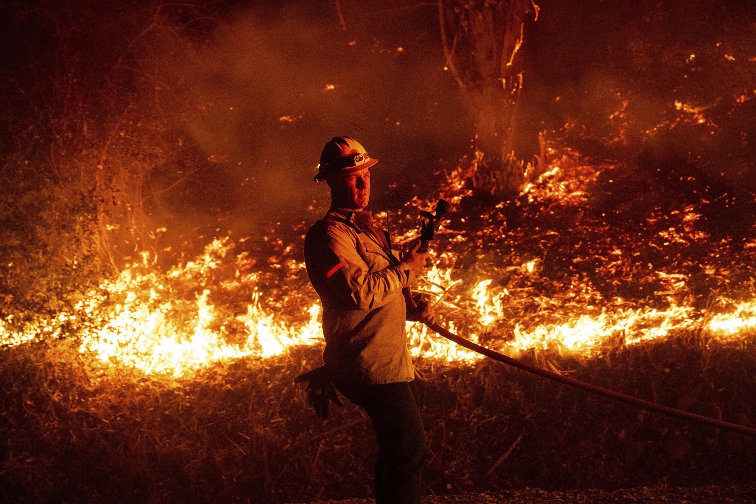 A firefighter prepares to douse flames while battling the Mountain Fire on Wednesday, Nov. 6, 2024, in Santa Paula, Calif.