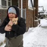 Lisa Muscat carries her dog Zoey to safety after a water main break in Detroit caused massive flooding, triggering evacuations, Monday, Feb. 17, 2025.