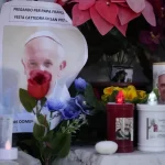 Candles are seen near pictures of Pope Francis outside the Agostino Gemelli Polyclinic in Rome, Sunday, Feb. 23, 2025, where the Pontiff is hospitalized since Feb. 14.