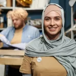 Woman in gray hijab smiling.