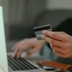 Close up of man hands using credit card online.