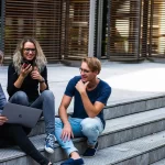 Three students sitting on the stairs talking with each other.