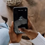 A person holding a smartphone displaying TikTok logo.