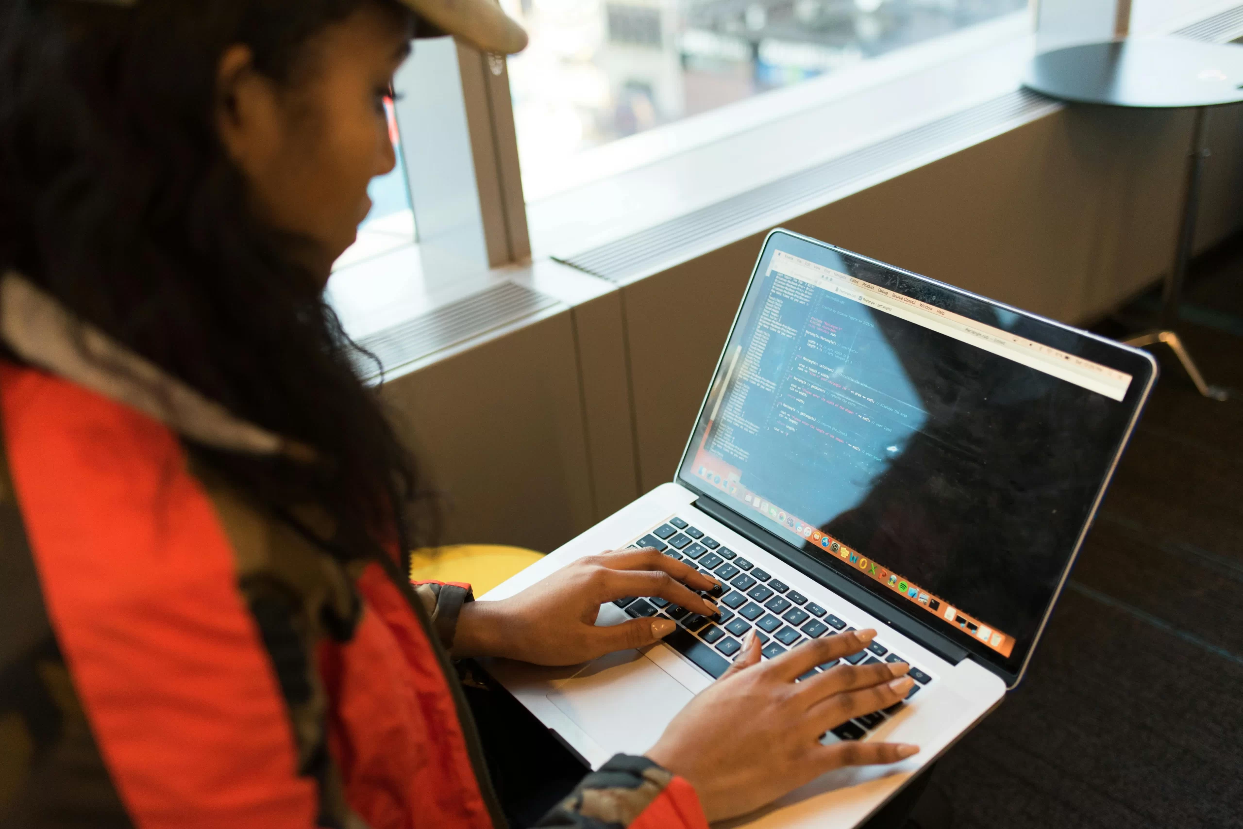 A woman using Macbook pro to code.