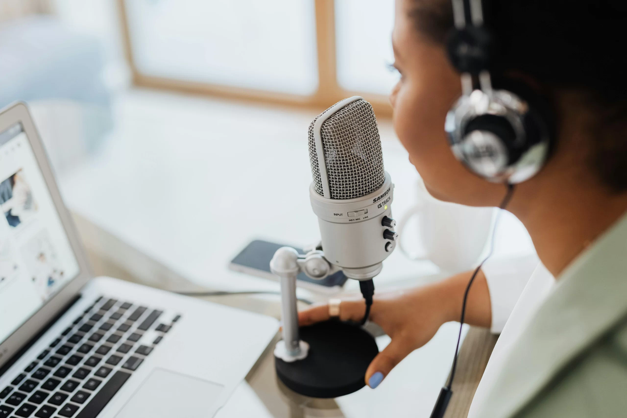 A content creator with headset speaking over a condenser microphone.