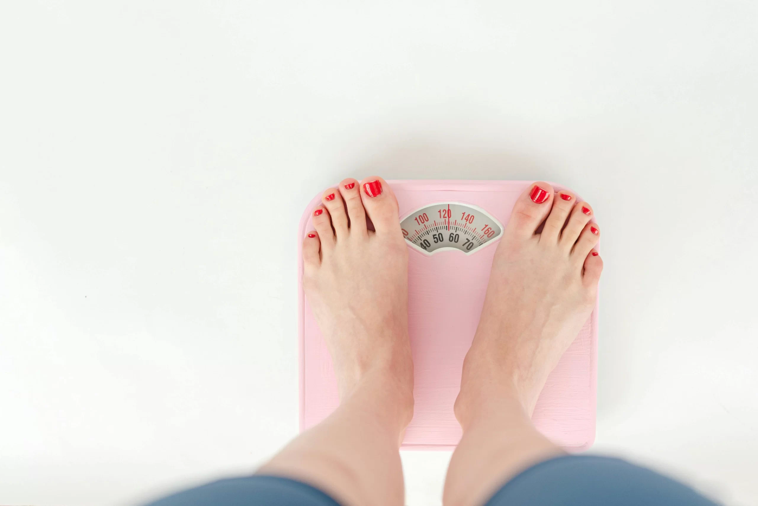 A woman weighing on scales in studio.