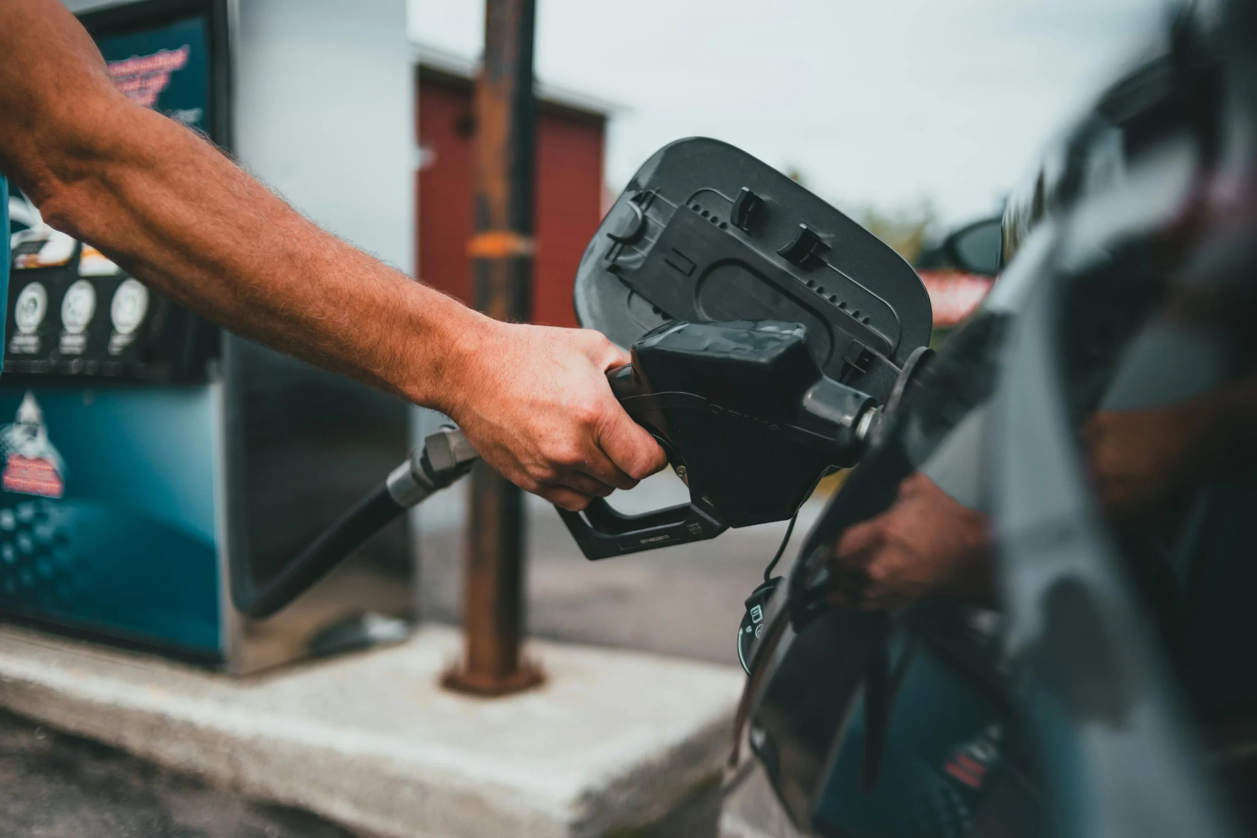A Person putting gasoline on a vehicle.