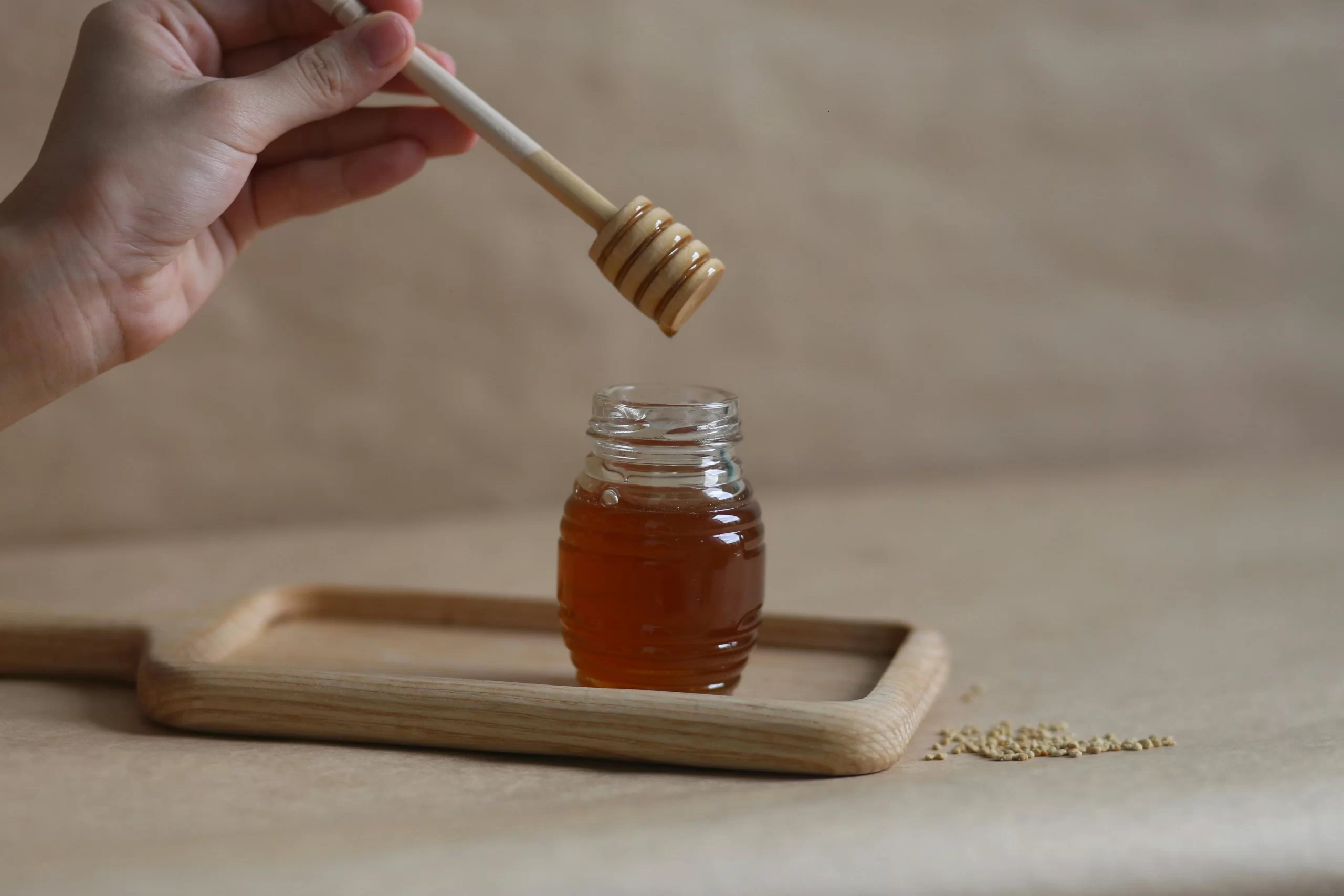 A hand holding a honey dipper.