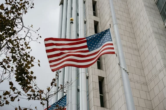 US flag flying in front of government building.