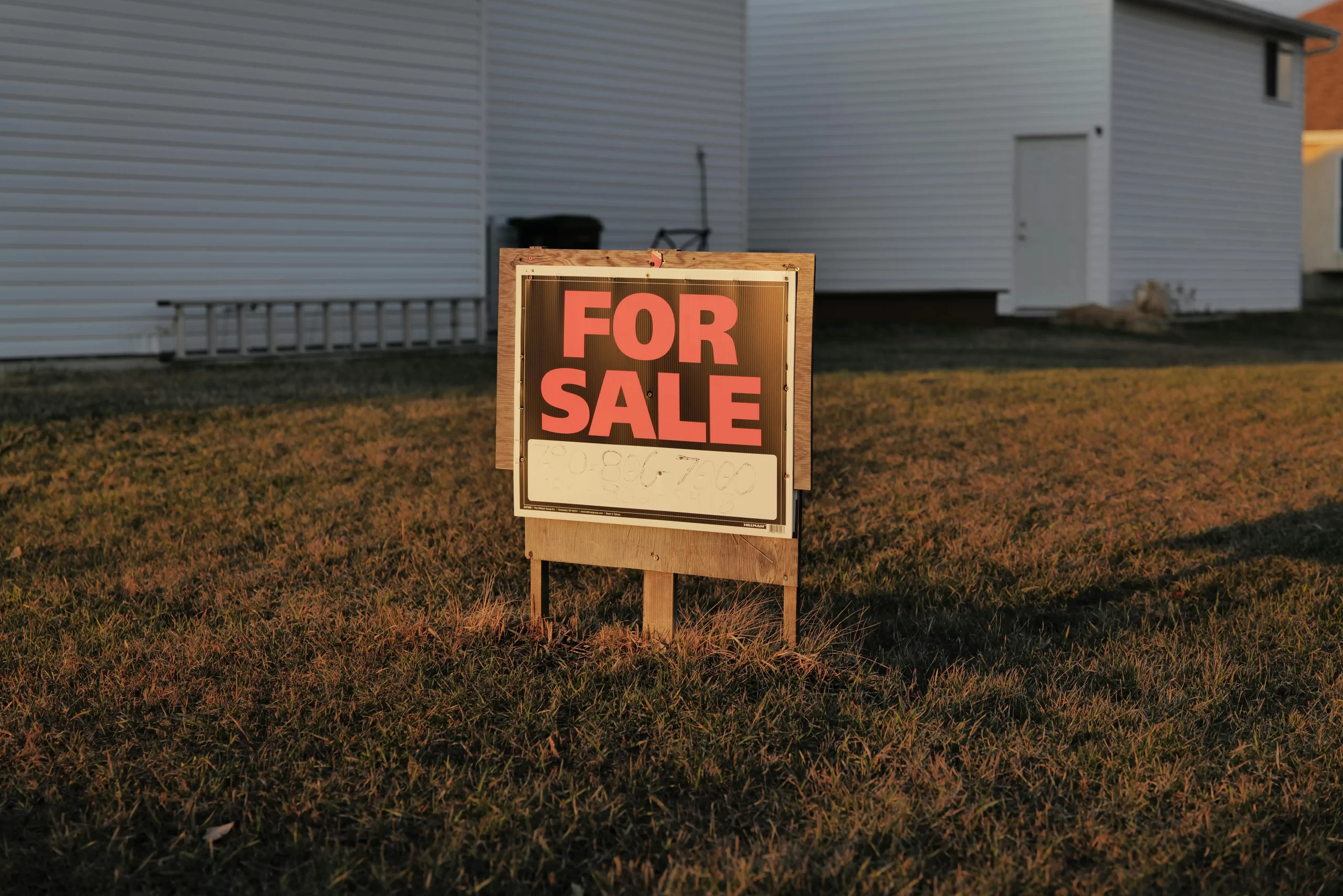 A 'For Sale' sign in a suburban yard, indicating a property for sale.