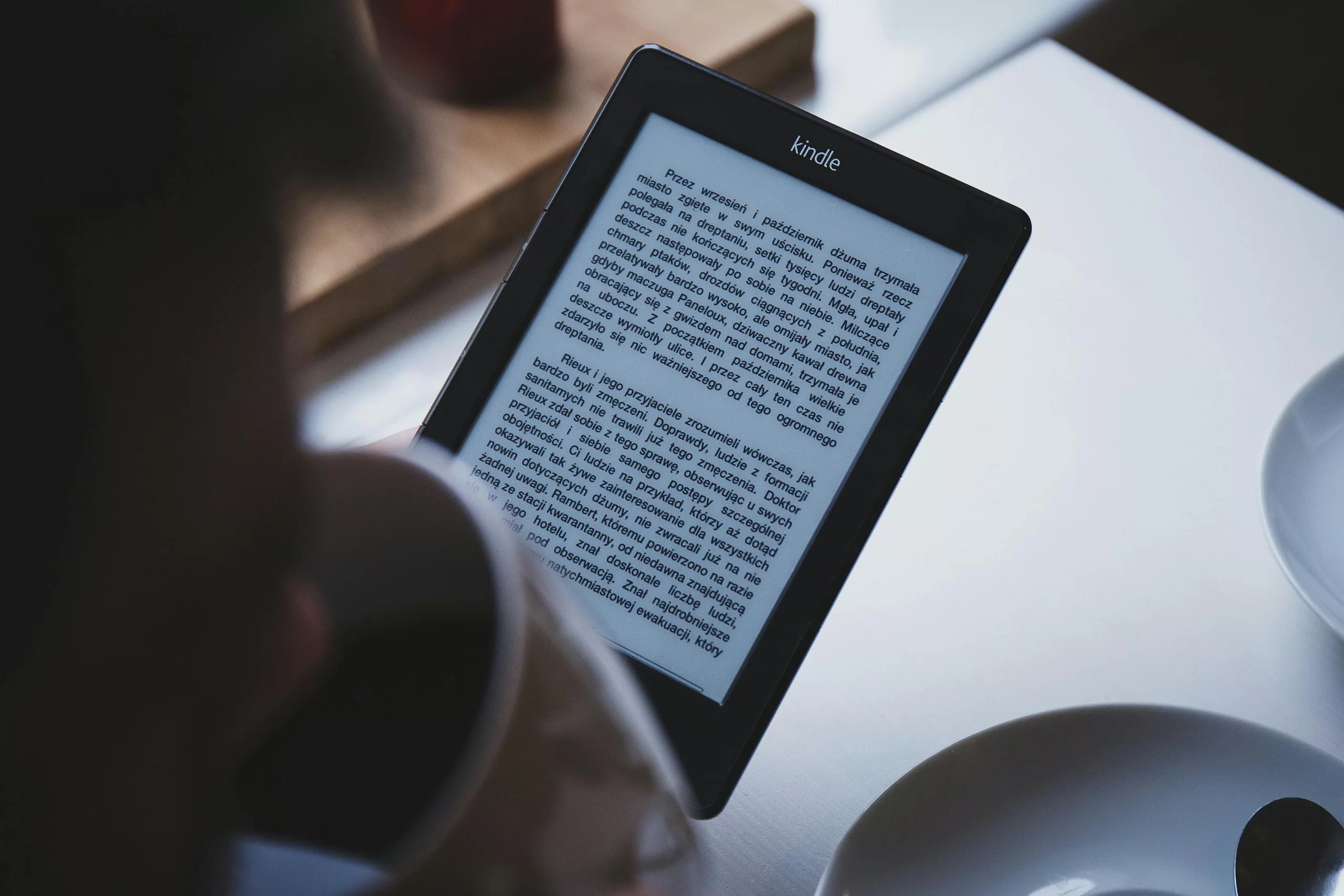 A person reads on a Kindle e-reader.