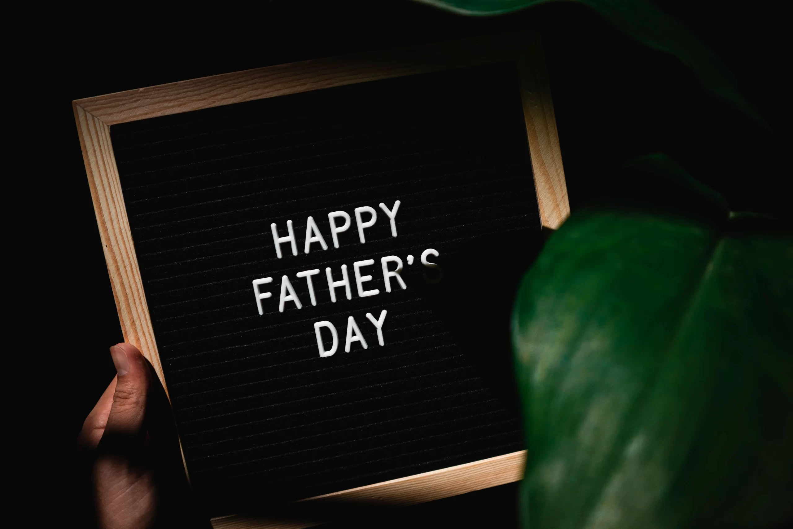 Letter board with 'Happy Father's Day' message held by hand.