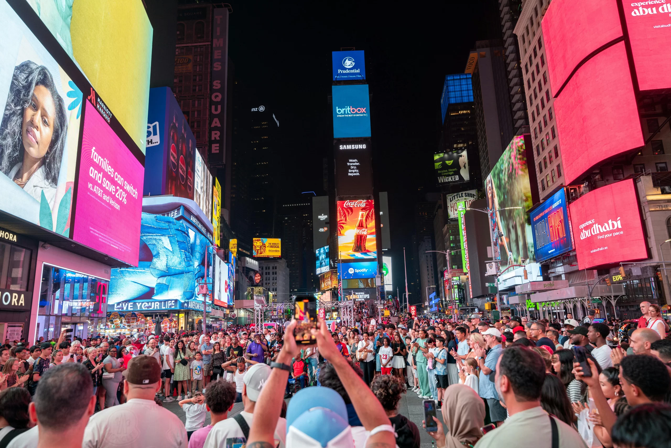 Crowds gather under bright billboards at Times Square, New York, capturing the vibrant city life.