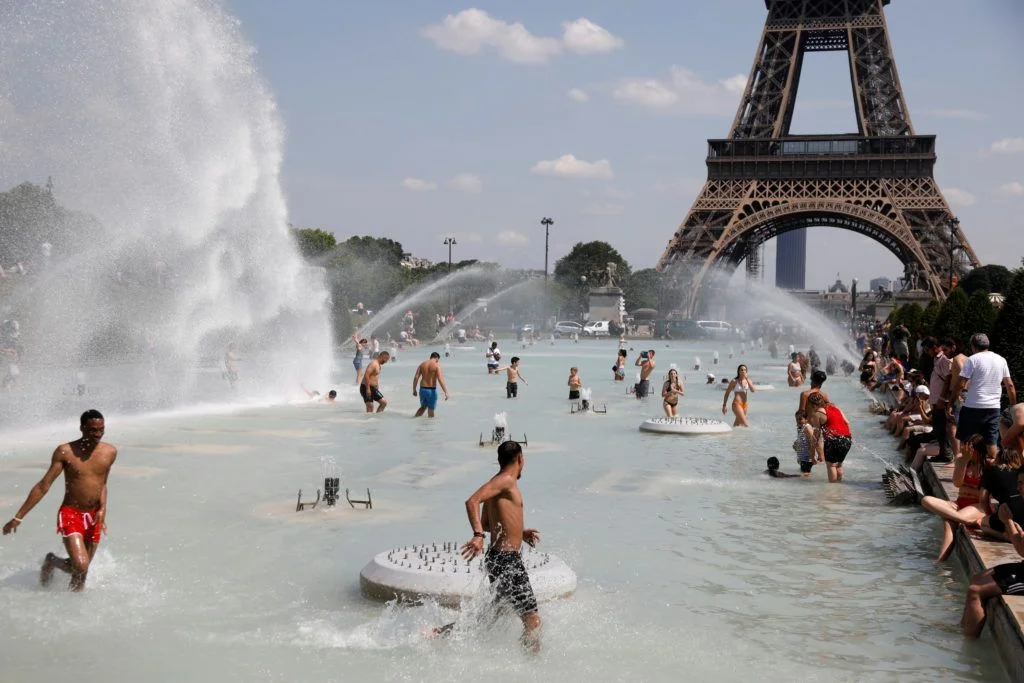 Parisians beat the heat by playing in the fountain near the Tour Eiffel.