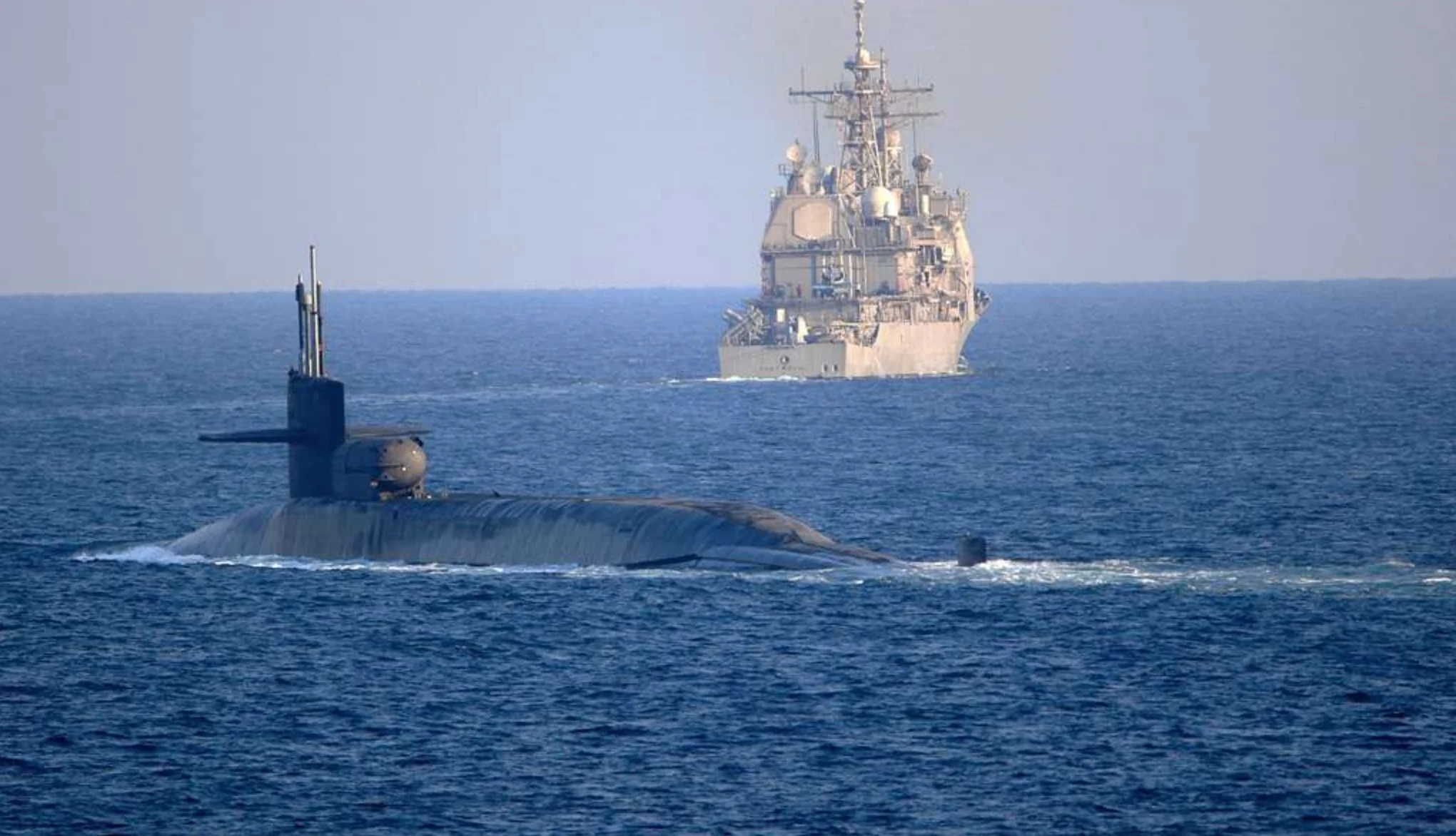 The guided-missile submarine USS Georgia (SSGN 729), front, transits the Strait of Hormuz.