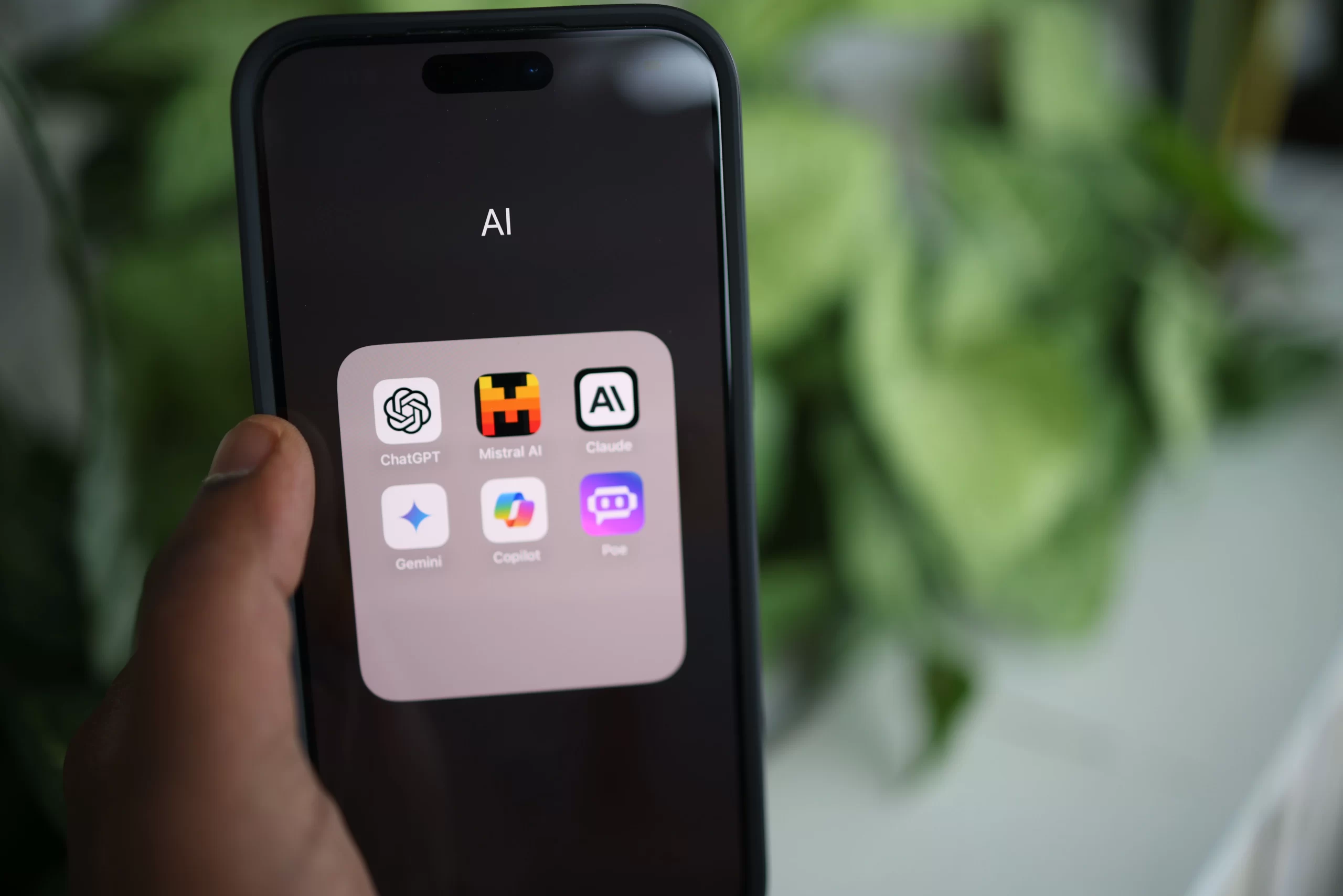 A hand holding a smartphone with AI applications on screen.