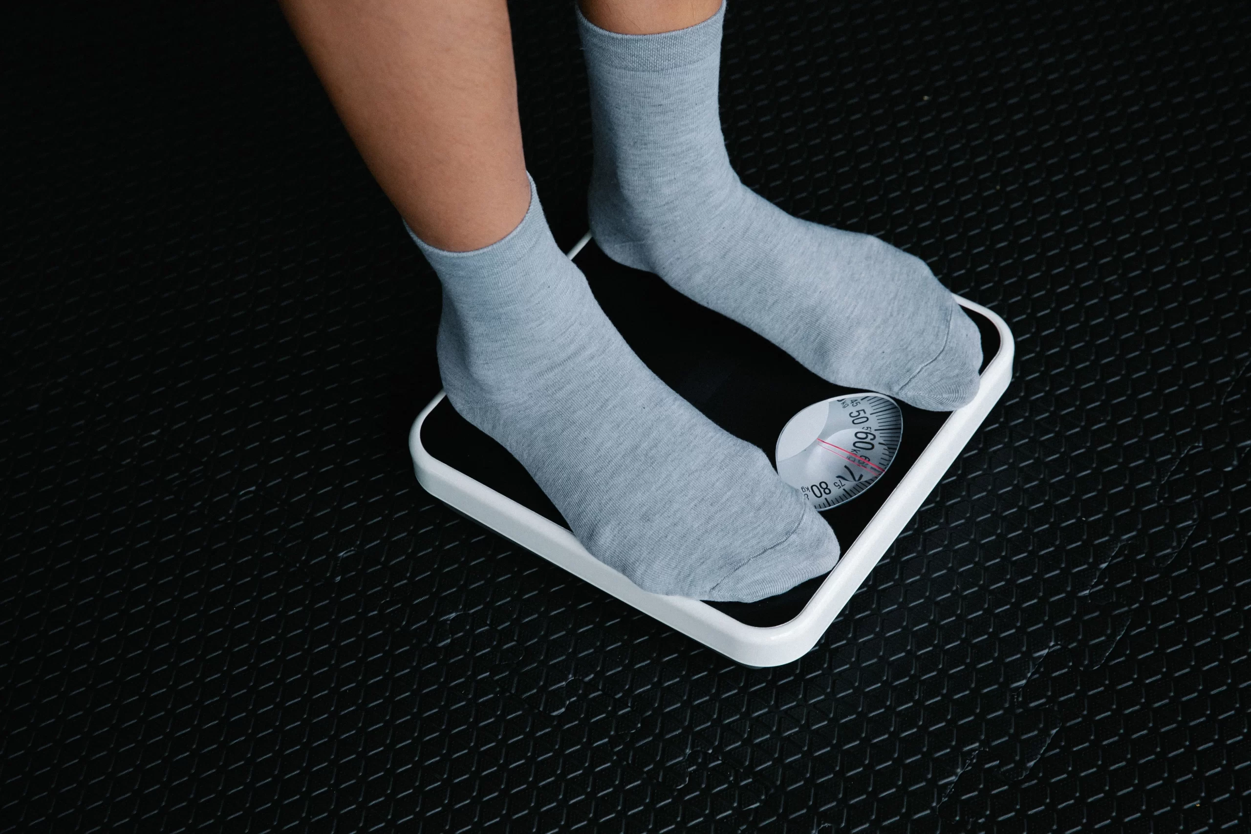 A person standing on a scale, focusing on weight measurement.