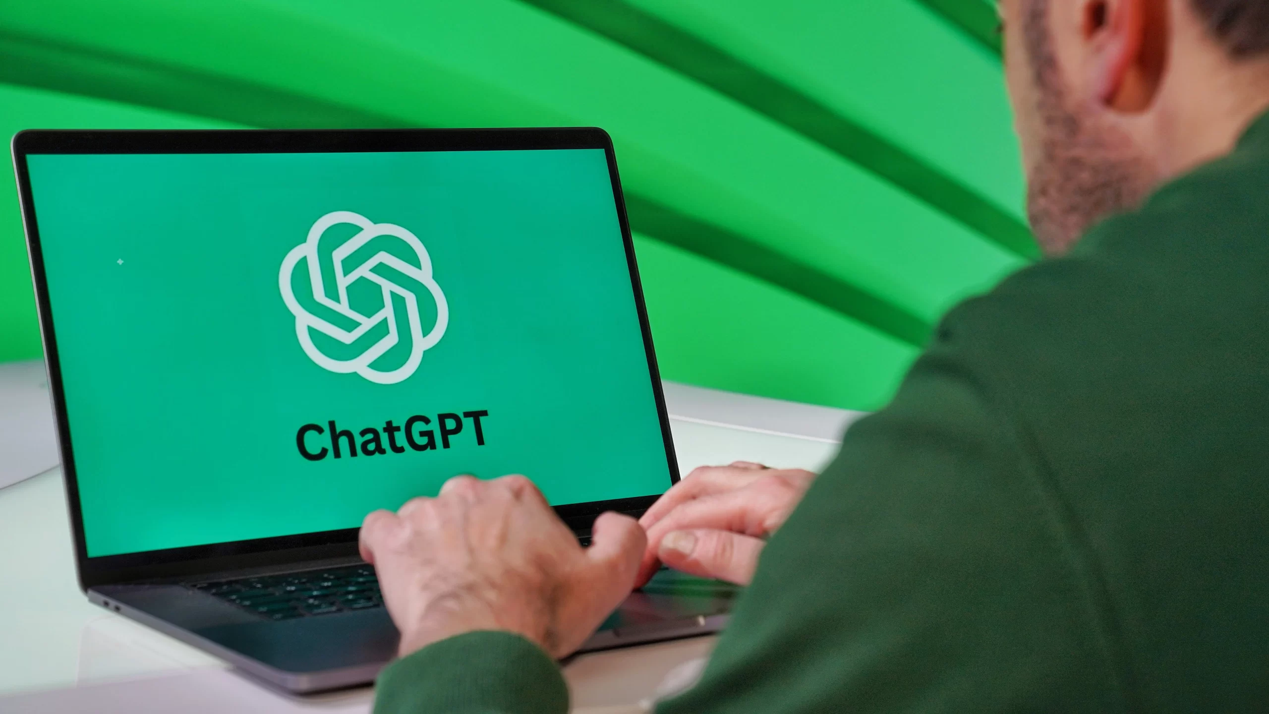 Person typing on a laptop displaying ChatGPT logo.
