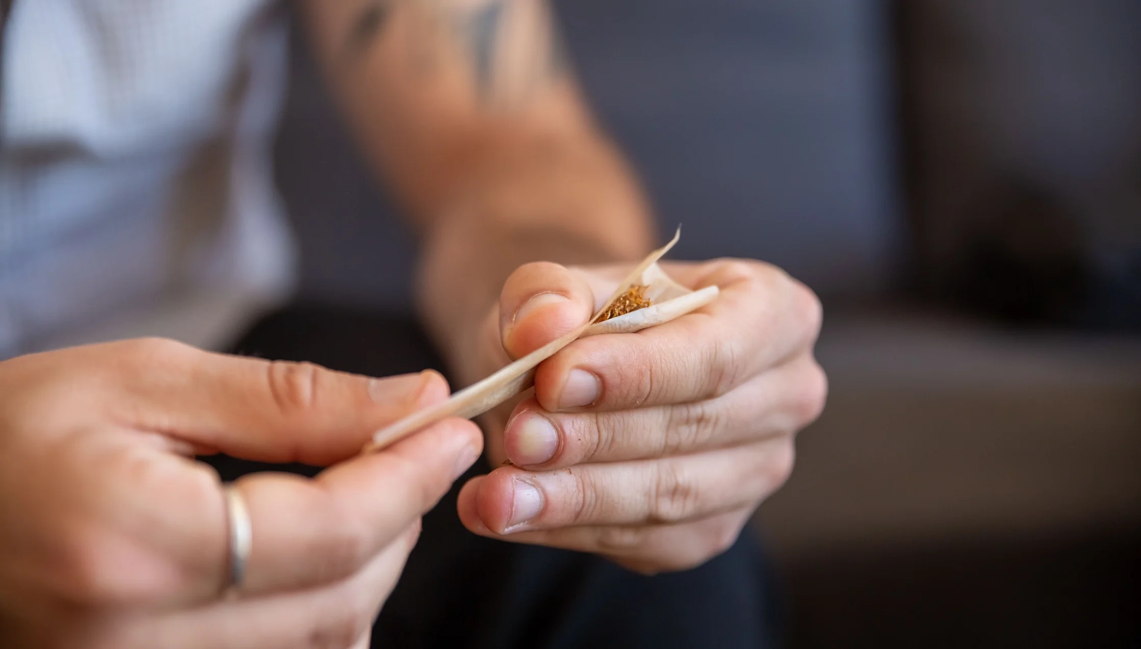 A detailed view of hands skillfully shaping a marijuana joint using rolling paper.