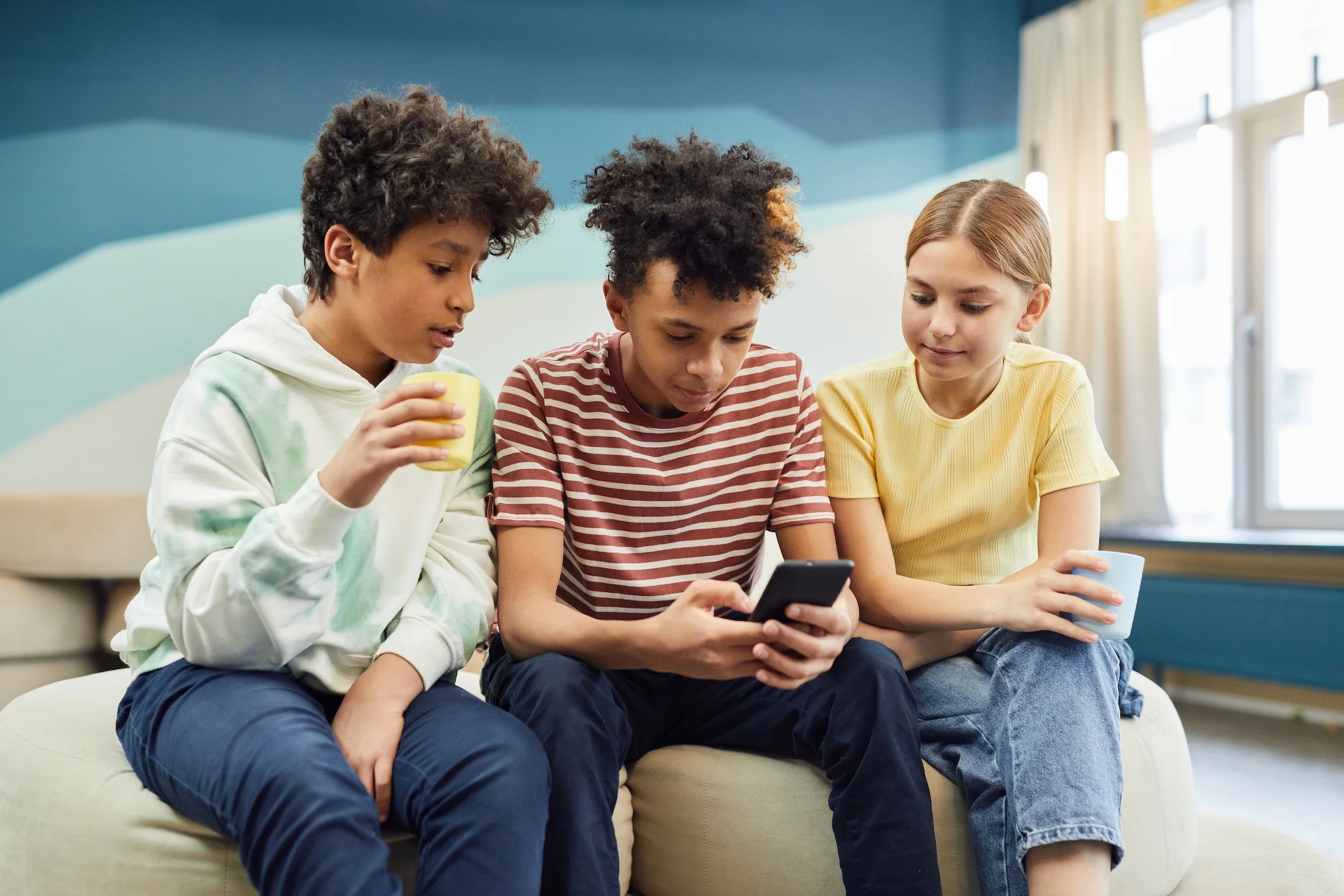 Three teenagers browsing a smartphone together.