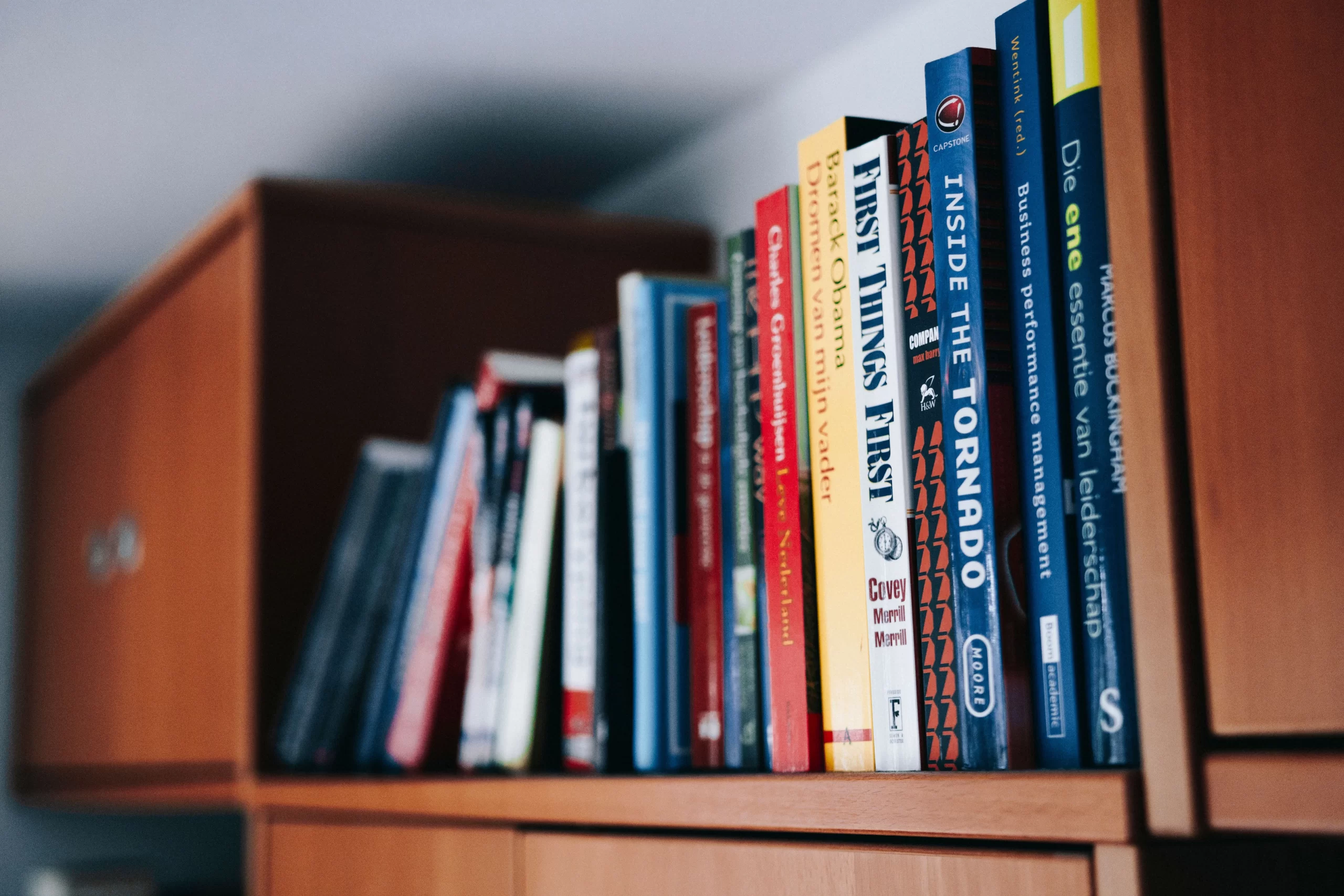 Books neatly arranged on a wooden bookshelf.