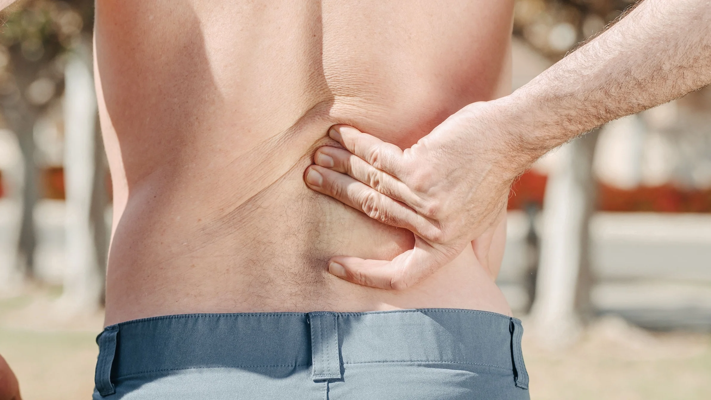 A man holding his lower back in pain, indicating discomfort or injury.