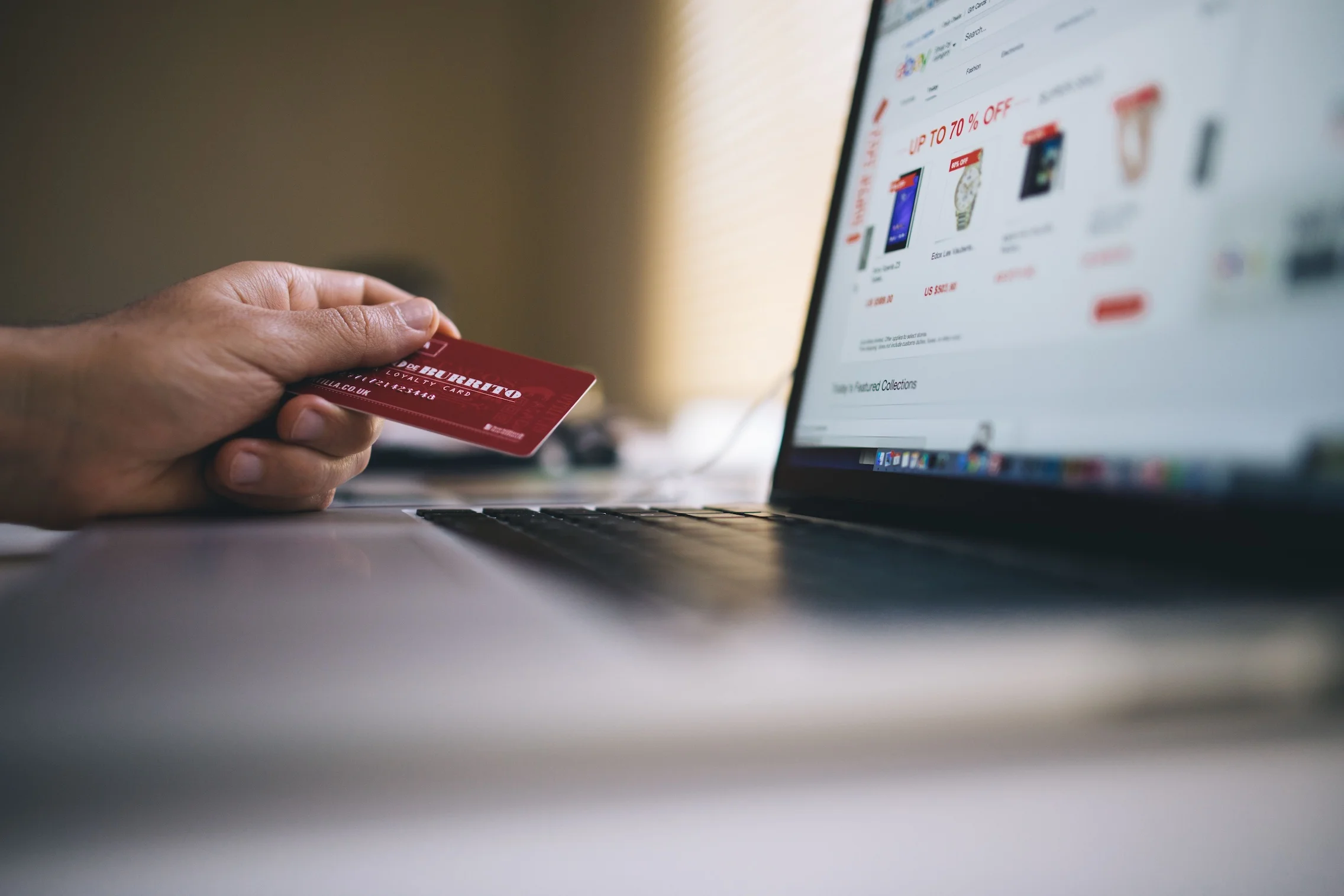 Person holding a credit card while shopping online, indicating ecommerce transactions.